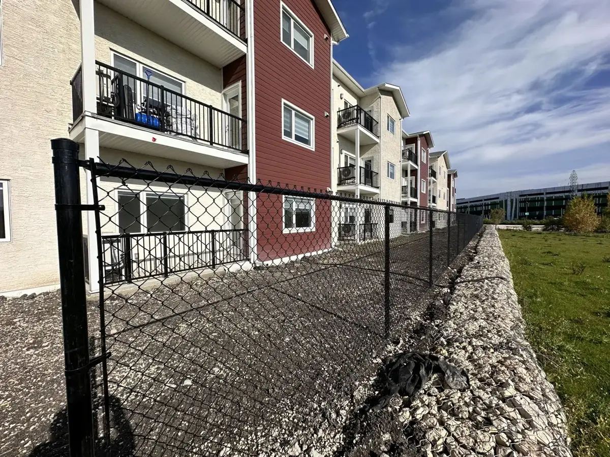 Black chain link fence behind an apartment building