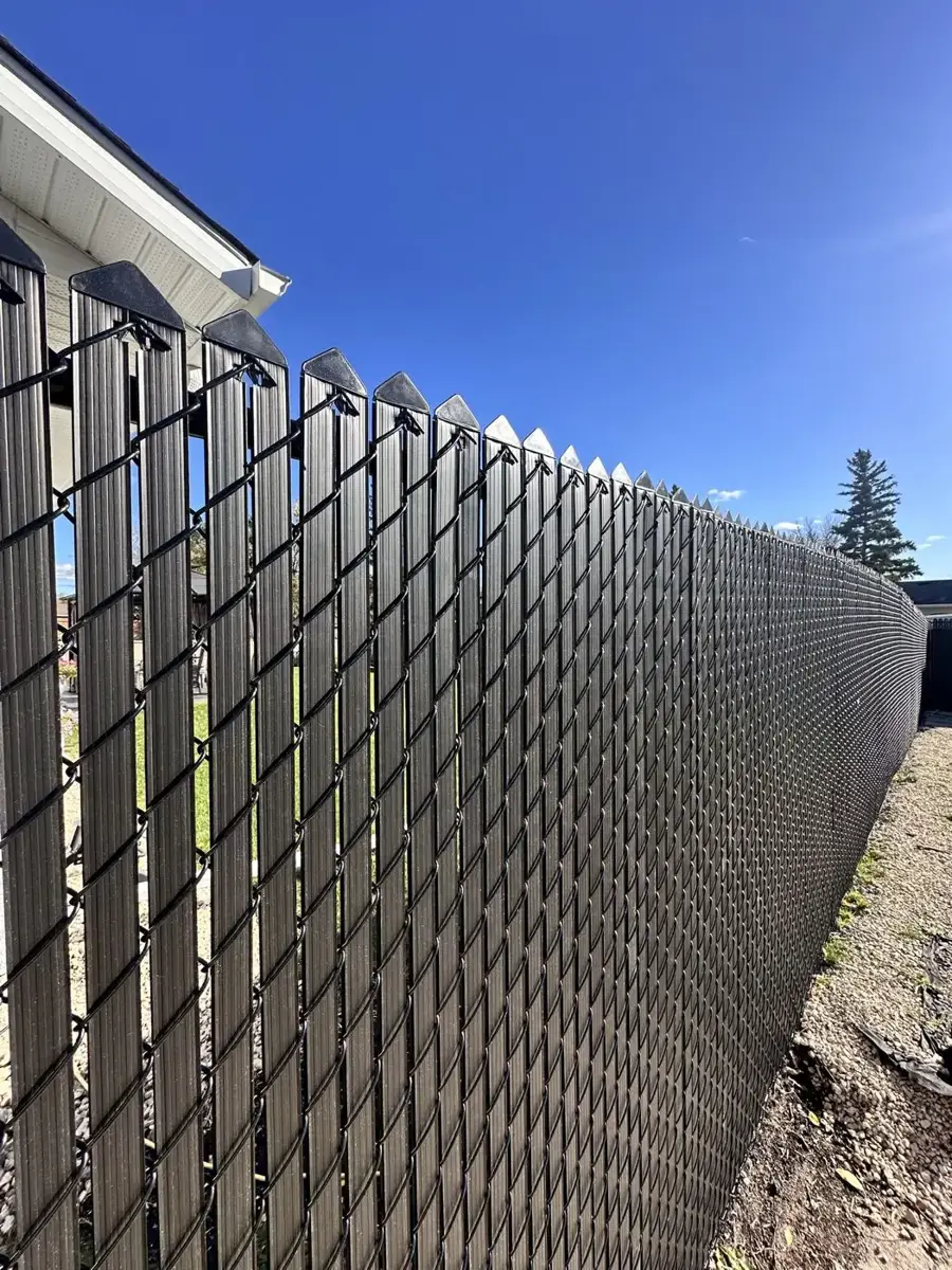 Close-up of black privacy slats woven through chain link fabric