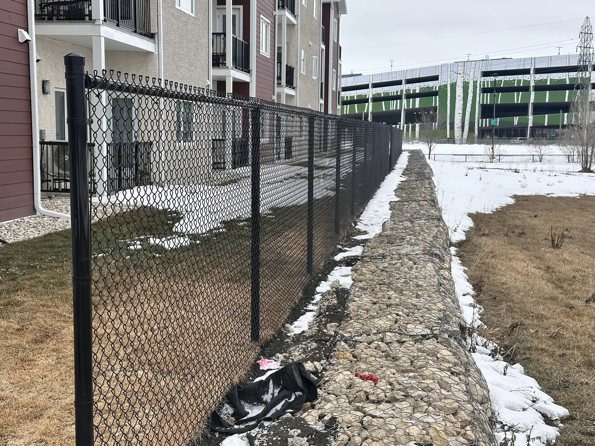 Black chain link fence beside an apartment building