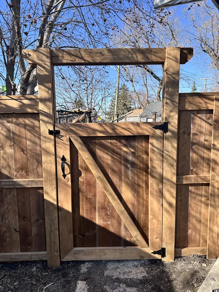 Cedar walk gate under a wood arbor in a vertical picket fence