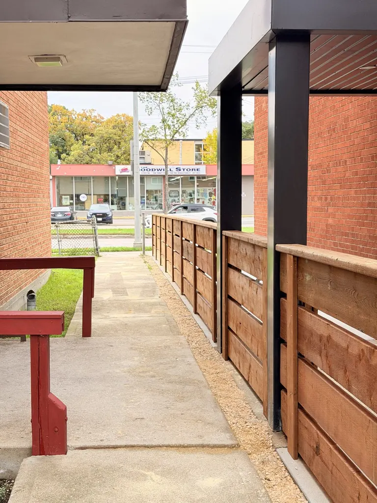 Horizontal cedar fence along an apartment walkway with the steel posts hidden behind the wood