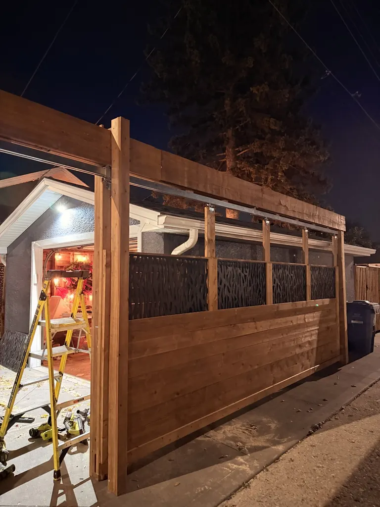 Finished overhead slide gate with horizontal cedar boards and decorative metal panels